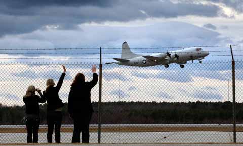 Naval Air Station Brunswick Women nod, wave after plane in Naval Air Station Brunswick